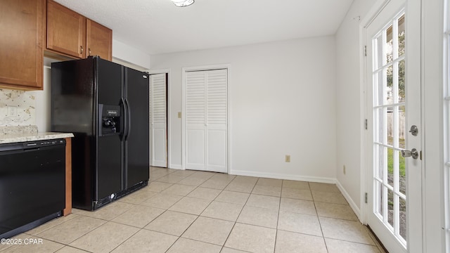 kitchen with tasteful backsplash, light tile patterned flooring, light stone countertops, and black appliances