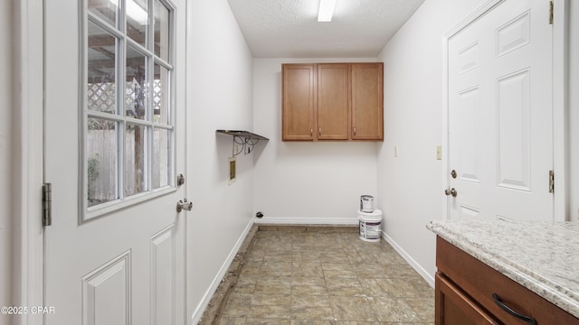 laundry area with washer hookup, cabinets, and a textured ceiling