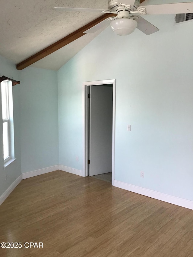 spare room featuring a textured ceiling, ceiling fan, wood-type flooring, and vaulted ceiling with beams