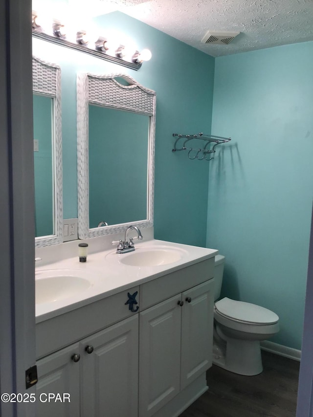 bathroom featuring toilet, vanity, a textured ceiling, and hardwood / wood-style floors