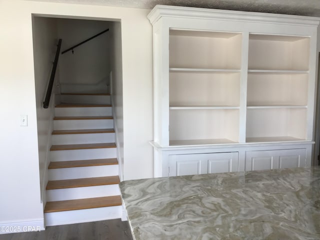 stairway with built in features and hardwood / wood-style flooring