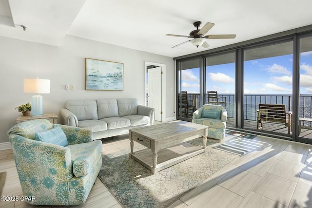 living room with a water view, expansive windows, ceiling fan, and light hardwood / wood-style floors