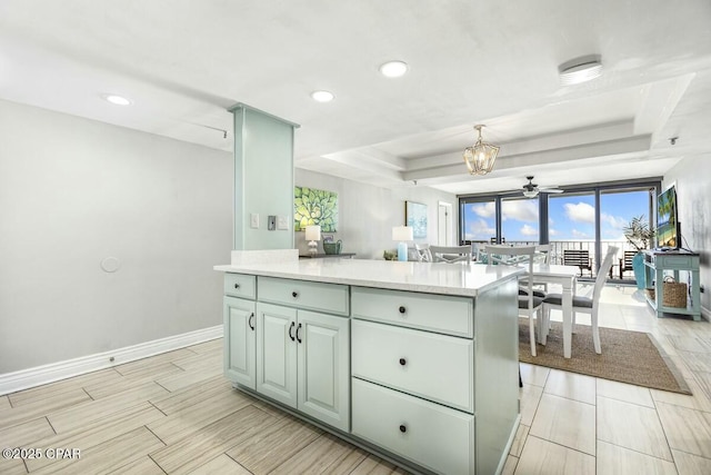 kitchen with decorative light fixtures, ceiling fan, a center island, a raised ceiling, and green cabinets