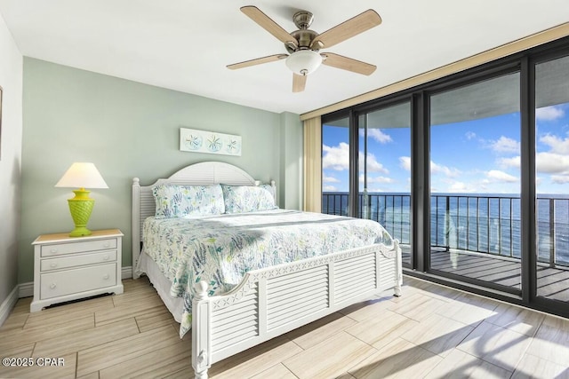 bedroom featuring ceiling fan, access to exterior, a water view, and expansive windows