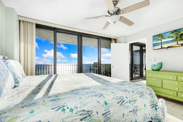 bedroom with light wood-type flooring, ceiling fan, a wall of windows, and access to outside