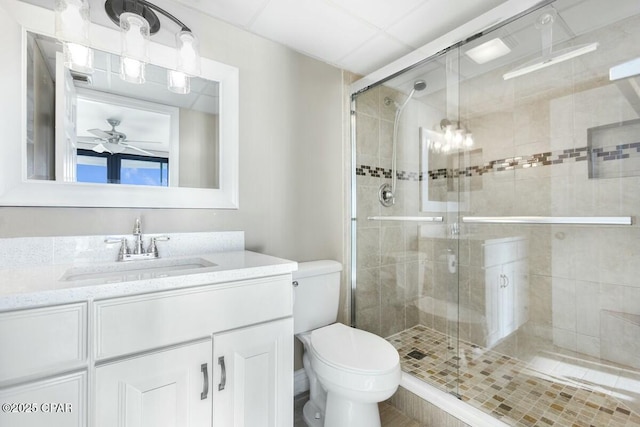 bathroom featuring ceiling fan, vanity, a shower with door, and toilet