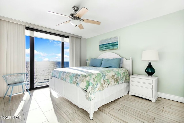 bedroom featuring ceiling fan, a wall of windows, access to outside, and a water view