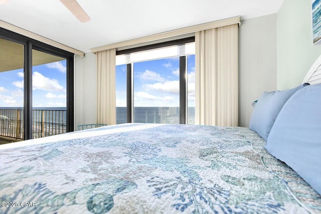 bedroom featuring a water view, a wall of windows, access to exterior, and ceiling fan