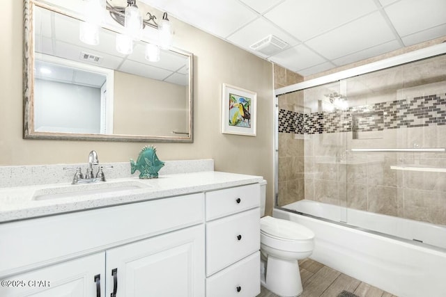 full bathroom featuring toilet, a paneled ceiling, enclosed tub / shower combo, and vanity