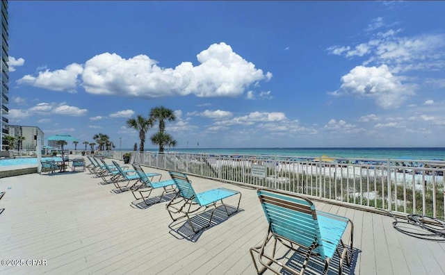 wooden deck with a water view and a beach view