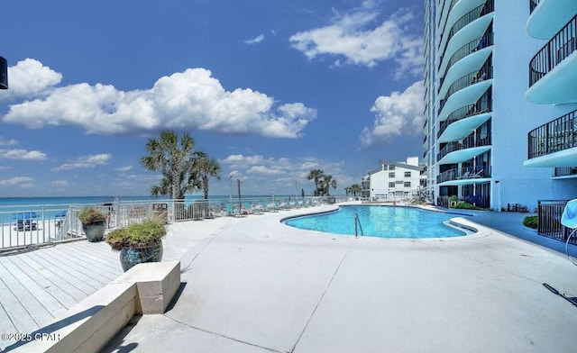 view of swimming pool with a water view and a patio