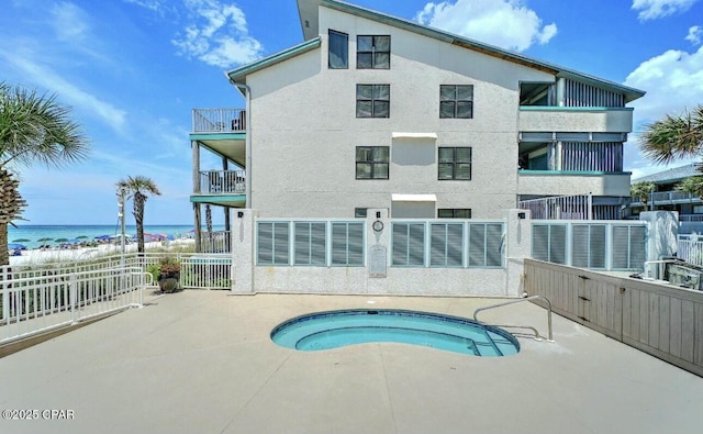 exterior space with a beach view, a hot tub, and a water view