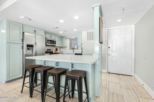 kitchen with sink, light stone countertops, a kitchen breakfast bar, and stainless steel appliances