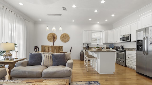 kitchen featuring white cabinetry, stainless steel appliances, decorative light fixtures, and a breakfast bar area