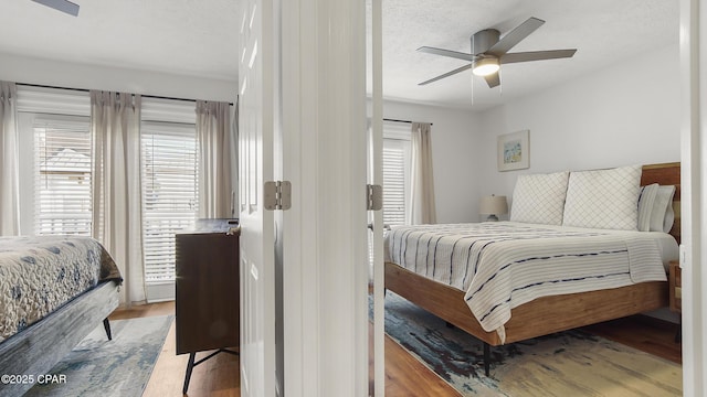 bedroom featuring ceiling fan, light hardwood / wood-style floors, and a textured ceiling