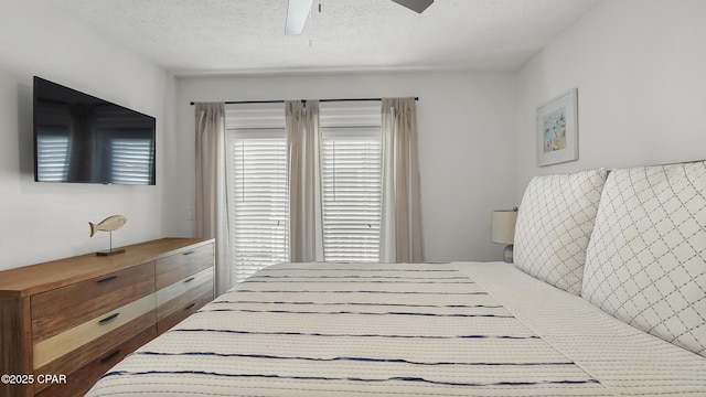 bedroom featuring multiple windows, ceiling fan, and a textured ceiling