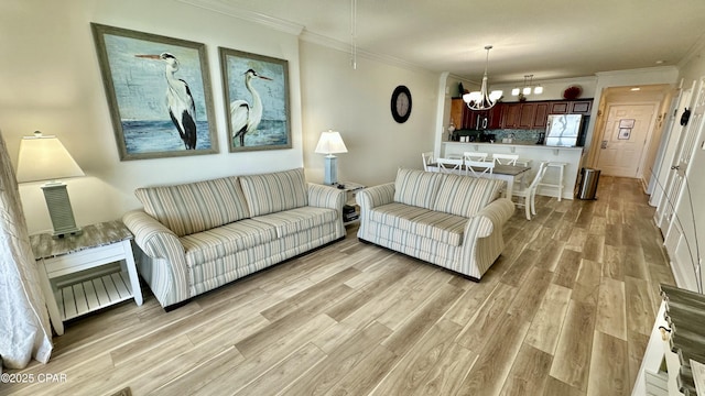 living room featuring a notable chandelier, ornamental molding, and light hardwood / wood-style flooring