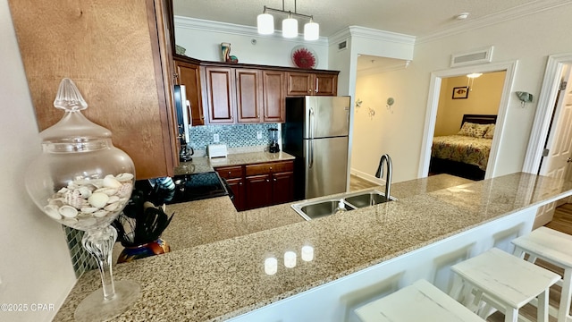 kitchen featuring kitchen peninsula, sink, a breakfast bar area, ornamental molding, and stainless steel fridge