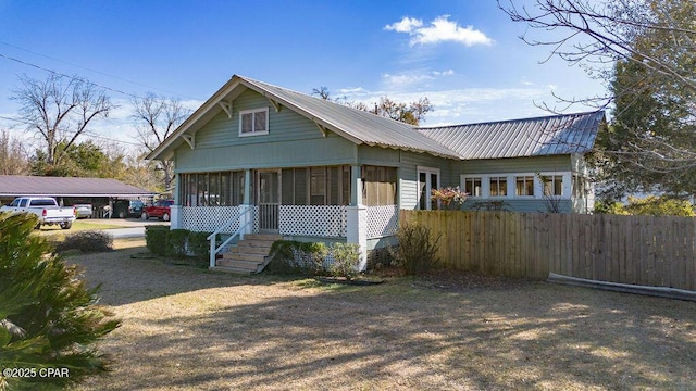 bungalow with a sunroom, fence, and metal roof