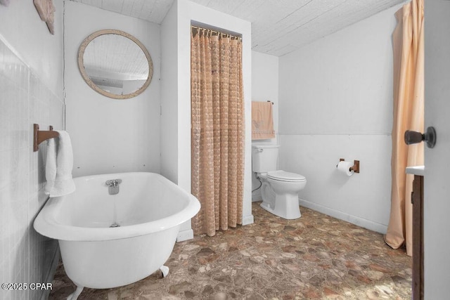 bathroom with a tub to relax in, toilet, and a textured ceiling