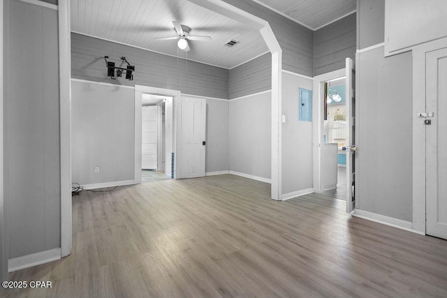 empty room with ceiling fan, electric panel, and hardwood / wood-style flooring