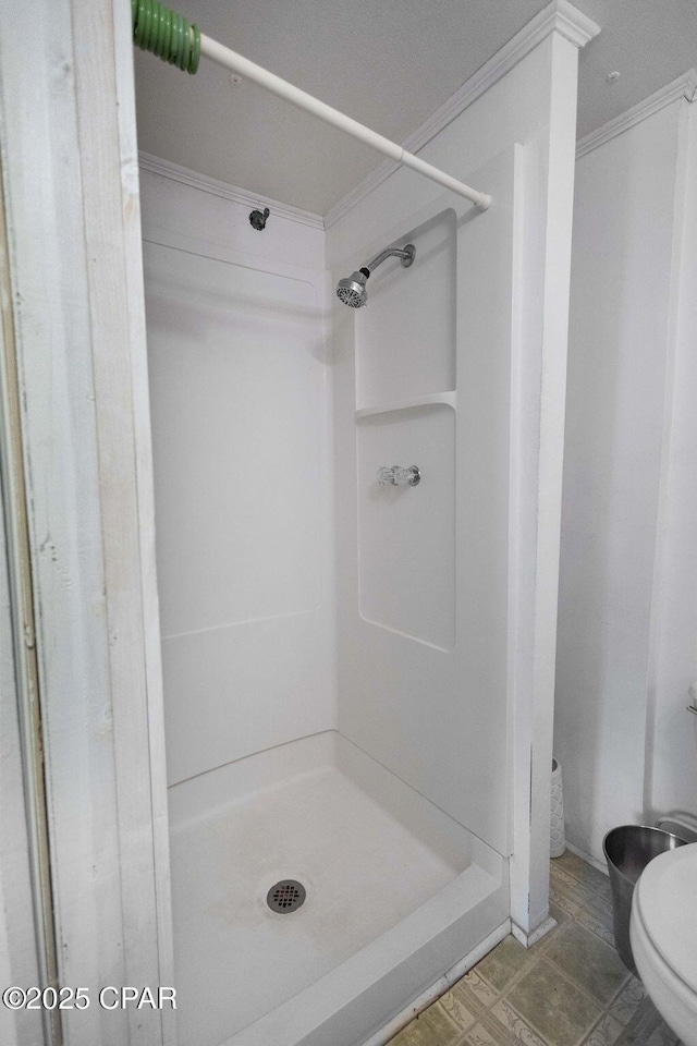 bathroom with a shower, toilet, and ornamental molding