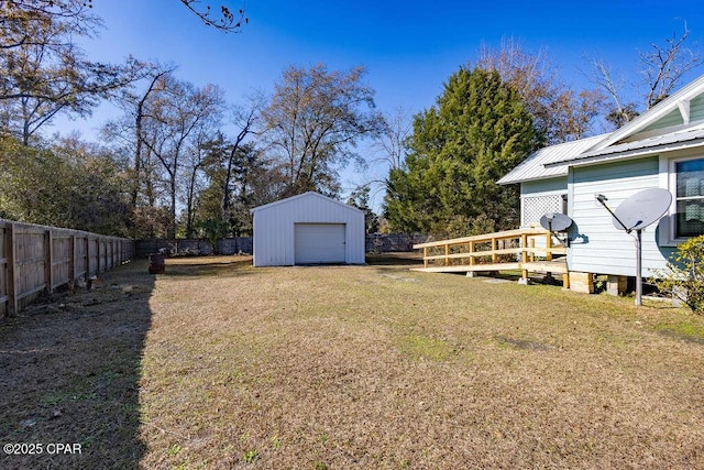 view of yard featuring a detached garage, a fenced backyard, an outdoor structure, and a deck