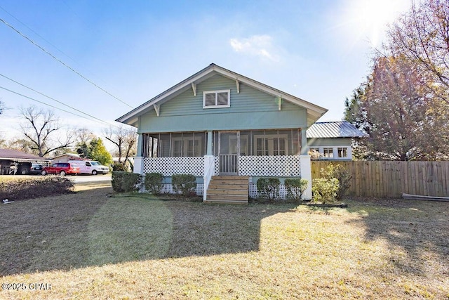 back of property with a sunroom and a lawn