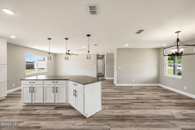 kitchen featuring visible vents, open floor plan, wood finished floors, and a center island