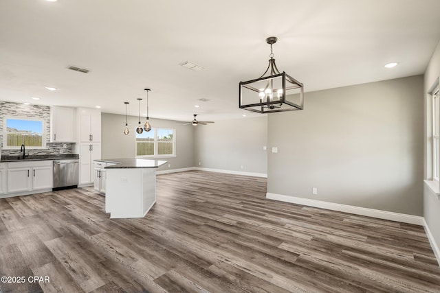 kitchen with tasteful backsplash, dark countertops, white cabinetry, wood finished floors, and dishwasher