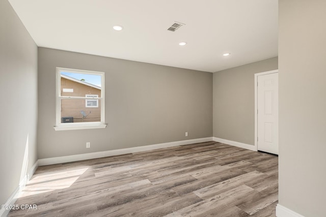 empty room featuring wood finished floors, visible vents, and baseboards