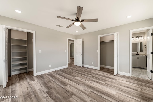 unfurnished bedroom with baseboards, visible vents, wood finished floors, a spacious closet, and a closet