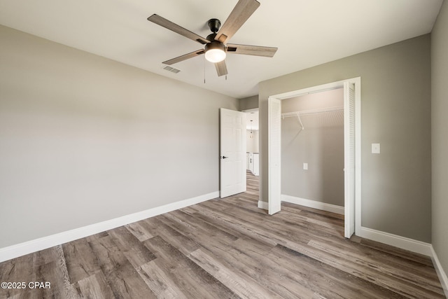 unfurnished bedroom featuring a closet, visible vents, baseboards, and wood finished floors