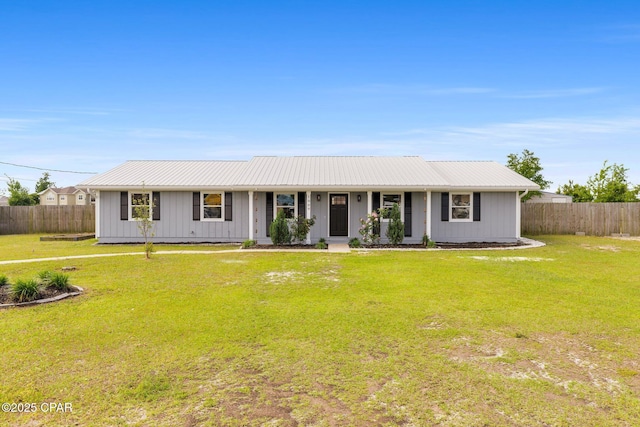 ranch-style home featuring metal roof, fence, and a front lawn