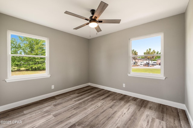 spare room featuring ceiling fan, baseboards, and wood finished floors