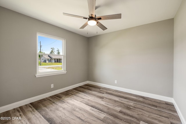 empty room with a ceiling fan, baseboards, and wood finished floors