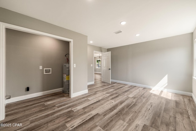 interior space featuring baseboards, visible vents, wood finished floors, electric water heater, and recessed lighting