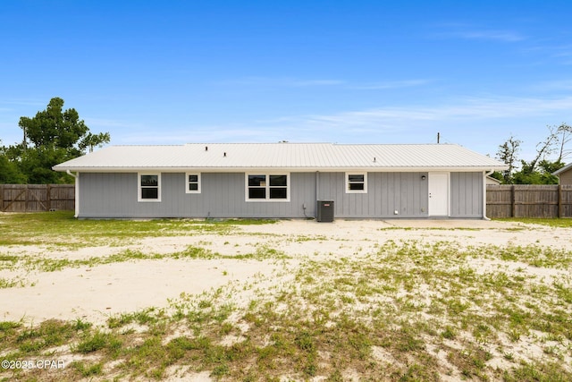 back of property with metal roof, central AC, and fence