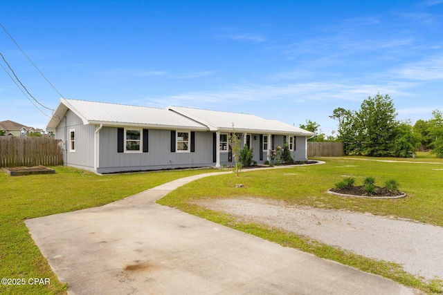 single story home featuring metal roof, driveway, a front lawn, and fence