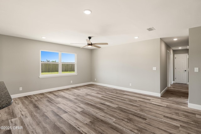 unfurnished room featuring wood finished floors, visible vents, and baseboards