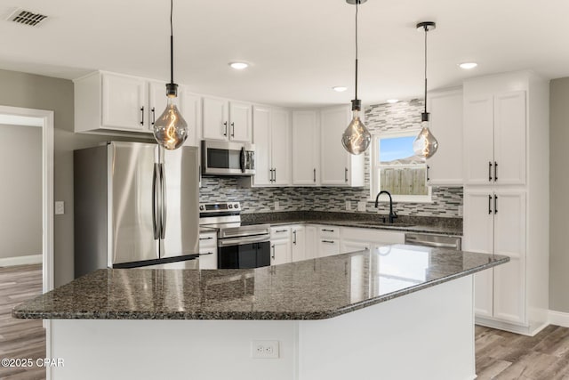 kitchen with appliances with stainless steel finishes, backsplash, a sink, and white cabinetry