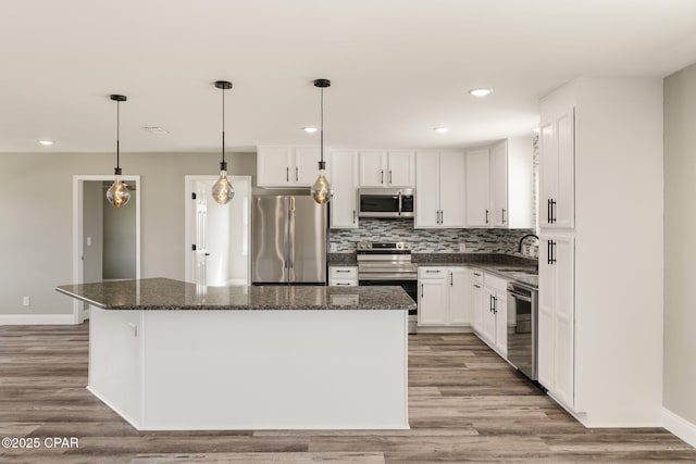 kitchen featuring tasteful backsplash, appliances with stainless steel finishes, a center island, white cabinetry, and a sink