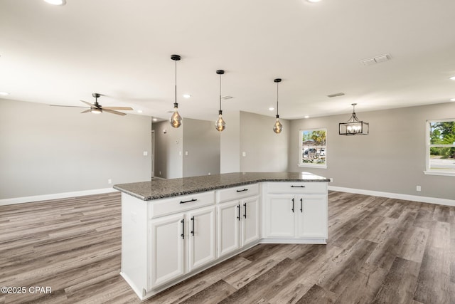 kitchen with light wood finished floors, baseboards, visible vents, open floor plan, and a center island