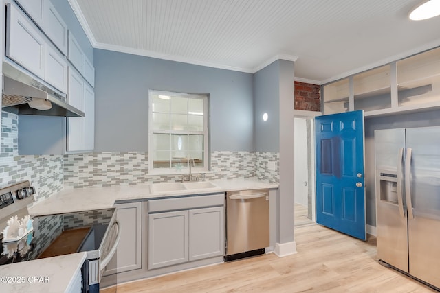 kitchen with appliances with stainless steel finishes, light hardwood / wood-style floors, ornamental molding, sink, and tasteful backsplash