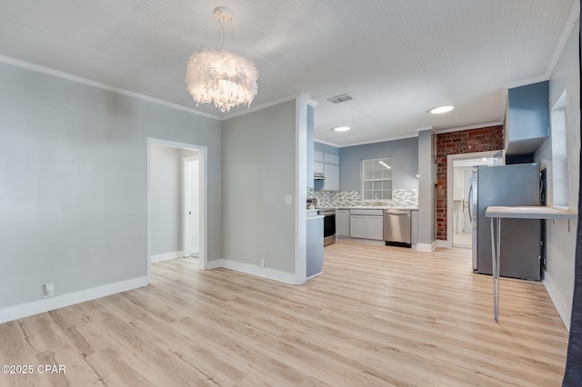 unfurnished living room featuring light hardwood / wood-style flooring, brick wall, a notable chandelier, crown molding, and sink