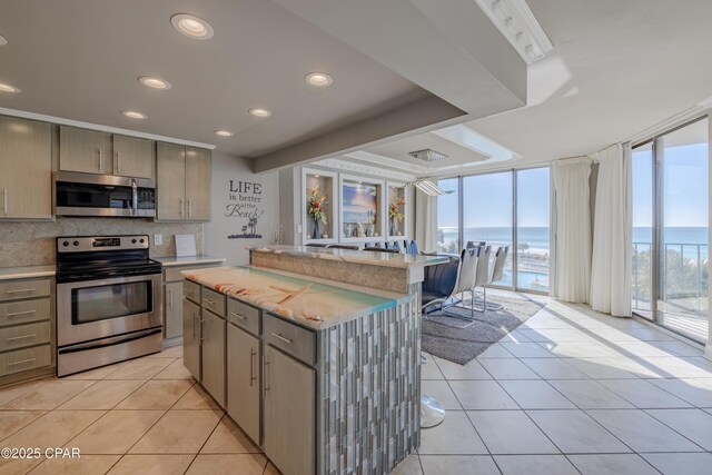 kitchen with a center island, a water view, expansive windows, decorative backsplash, and appliances with stainless steel finishes