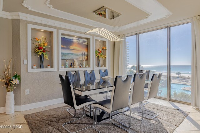 tiled dining area with a water view and crown molding