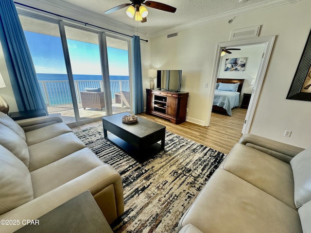 living room featuring ornamental molding, a textured ceiling, ceiling fan, and hardwood / wood-style floors