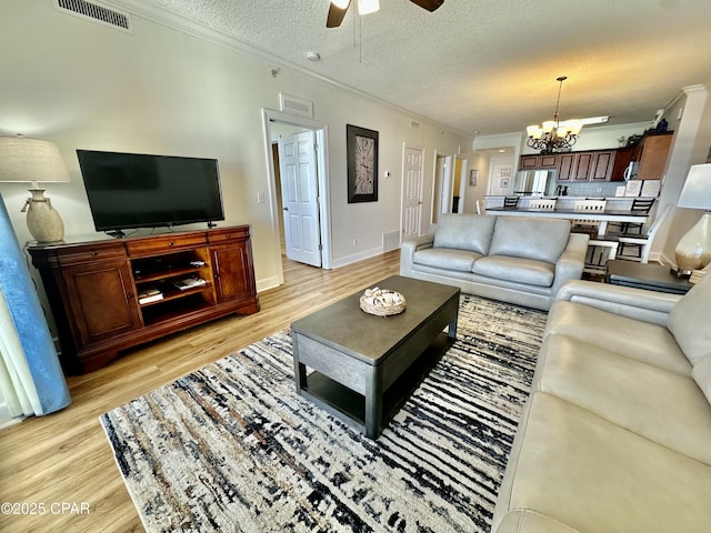 living room featuring ornamental molding, a textured ceiling, and light hardwood / wood-style floors