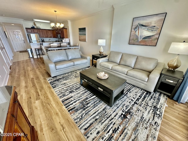 living room featuring an inviting chandelier, light hardwood / wood-style floors, crown molding, and a textured ceiling